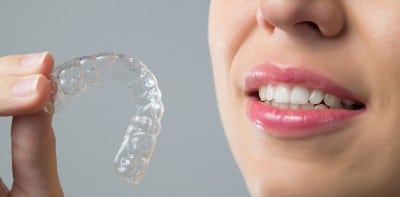 smiling woman with an Invisalign aligner