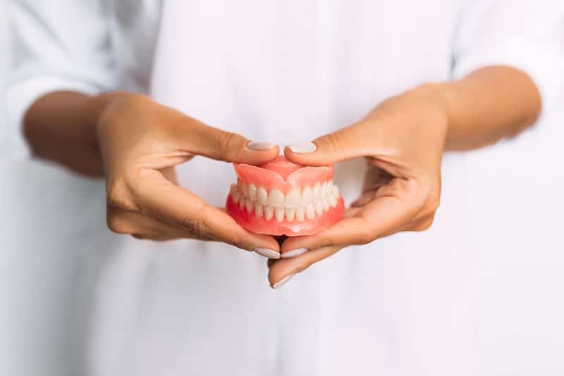 female dentist holding a pair of traditional dentures