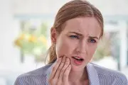  la mujer masajea su mandíbula para reducir el dolor mientras está en casa