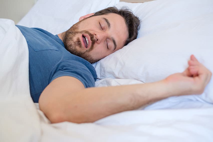 man laying on his back, snoring in bed