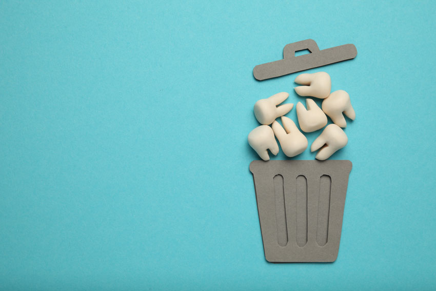 fake teeth in a paper cut out trash can on blue background
